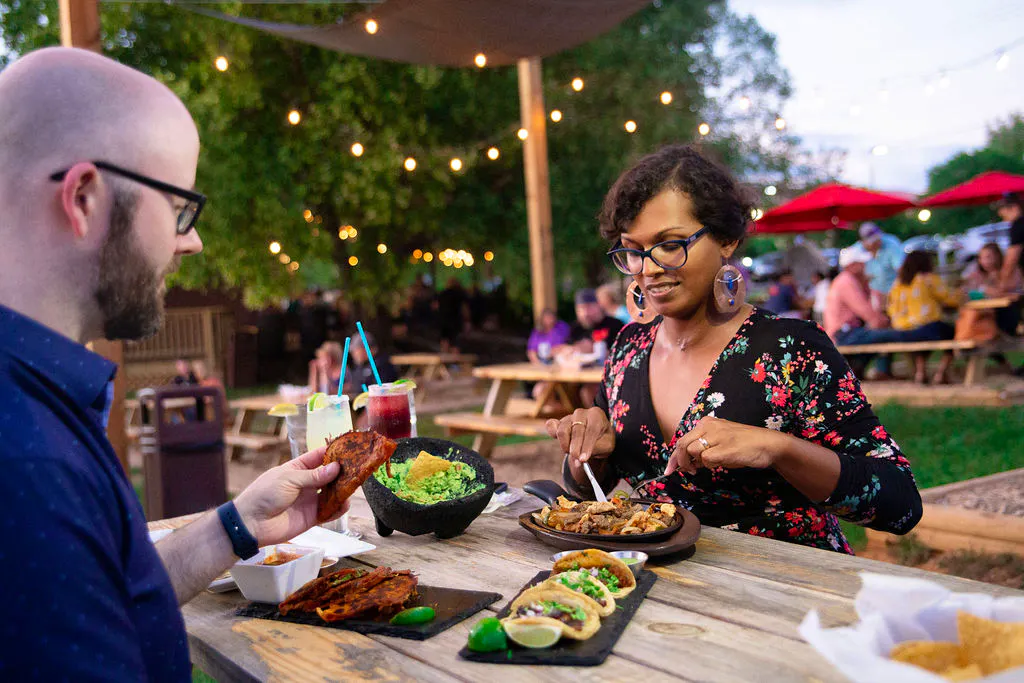 A couple sitting outside of Plaza Antigua enjoying tacos, fajitas, guac, and drinks.