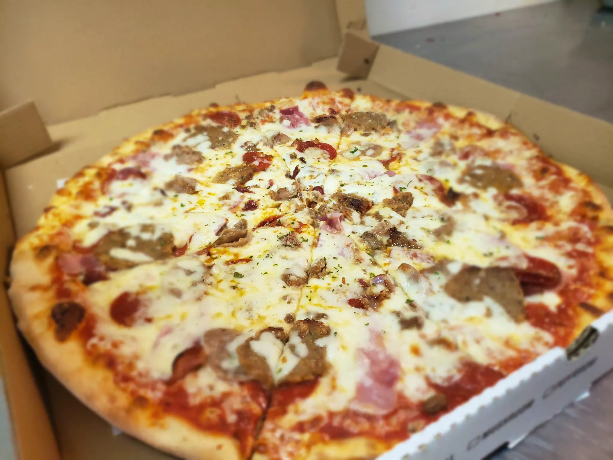 Picture of a pizza with meat and cheese at New York Flying Pizza