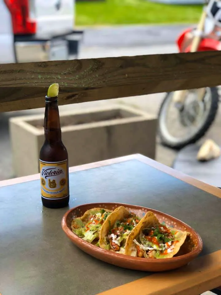 A picture of tacos and a beer outside of La Sabrosita with a motorcycle in the background.